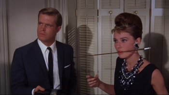 Movie still from “Breakfast at Tiffany's” (1961), directed by Blake Edwards – A man and a woman are smoking a cigarette together; Medium shot, Over the shoulder angle