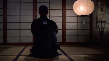 Movie still from “Breakfast at Tiffany's” (1961), directed by Blake Edwards – A man sitting on the ground in front of a wall; Medium shot, Low angle