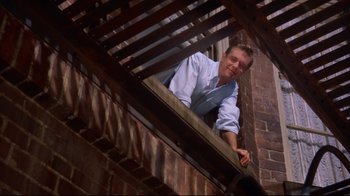 Movie still from “Breakfast at Tiffany's” (1961), directed by Blake Edwards – A man leaning up against a railing on a building; Medium shot, Low angle