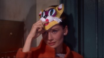 Movie still from “Breakfast at Tiffany's” (1961), directed by Blake Edwards – A woman wearing a cat mask in front of her face; Close Up shot, High angle
