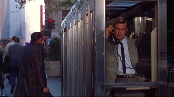 Movie still from “Breakfast at Tiffany's” (1961), directed by Blake Edwards – A man in a suit and tie talking on a phone; Medium shot, Over the shoulder angle