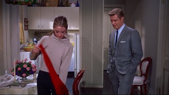 Movie still from “Breakfast at Tiffany's” (1961), directed by Blake Edwards – A man and a woman in a kitchen holding a red umbrella; Medium shot, Over the shoulder angle