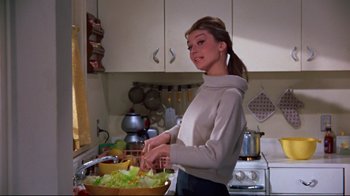 Movie still from “Breakfast at Tiffany's” (1961), directed by Blake Edwards – A woman in a kitchen preparing a salad; Medium shot, Low angle