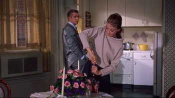 Movie still from “Breakfast at Tiffany's” (1961), directed by Blake Edwards – A man and a woman are cutting a cake together; Medium shot, Over the shoulder angle