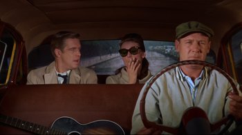 Movie still from “Breakfast at Tiffany's” (1961), directed by Blake Edwards – A group of people sitting in the back of a car; Medium shot, Over the shoulder angle