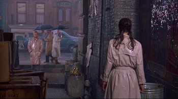 Movie still from “Breakfast at Tiffany's” (1961), directed by Blake Edwards – A woman wearing a trench coat and holding an umbrella; Wide shot, High angle