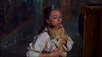Movie still from “Breakfast at Tiffany's” (1961), directed by Blake Edwards – A woman holding an orange cat in her arms; Medium shot, High angle