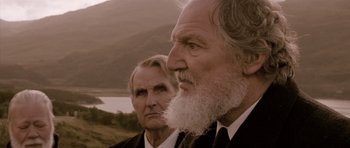 Two older men in suits and ties looking at each other