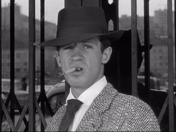 Movie still from “Breathless” (1960), directed by Jean-Luc Godard – A black and white photo of a man smoking a cigarette; Close Up shot, Low angle