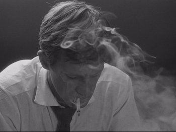 Movie still from “Breathless” (1960), directed by Jean-Luc Godard – A black and white photo of a man smoking a cigarette; Close Up shot, Low angle