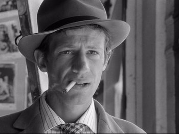 Movie still from “Breathless” (1960), directed by Jean-Luc Godard – A black and white photo of a man smoking a cigarette; Close Up shot, Low angle