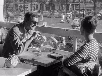 Movie still from “Breathless” (1960), directed by Jean-Luc Godard – A man sitting at a table with another man; Medium shot, Over the shoulder angle