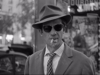 Movie still from “Breathless” (1960), directed by Jean-Luc Godard – A black and white photo of a man smoking a cigarette; Close Up shot, Low angle