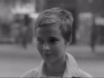Movie still from “Breathless” (1960), directed by Jean-Luc Godard – A black - and - white photo of a young girl's face; Close Up shot, Over the shoulder angle