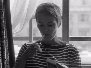 Movie still from “Breathless” (1960), directed by Jean-Luc Godard – A woman is painting a picture in front of a window; Close Up shot, High angle