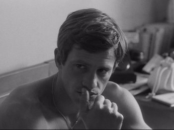 Movie still from “Breathless” (1960), directed by Jean-Luc Godard – Black and white photograph of a young man in a room; Close Up shot, High angle
