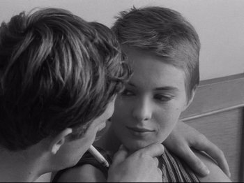 Movie still from “Breathless” (1960), directed by Jean-Luc Godard – A young boy and a young girl are looking at one another; Close Up shot, Over the shoulder angle