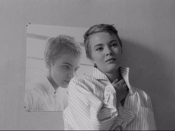 Movie still from “Breathless” (1960), directed by Jean-Luc Godard – Black and white photograph of a woman in front of a picture of herself; Close Up shot, High angle
