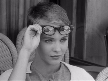 Movie still from “Breathless” (1960), directed by Jean-Luc Godard – A young woman wearing a pair of eye glasses; Close Up shot, Over the shoulder angle