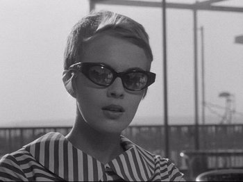 Movie still from “Breathless” (1960), directed by Jean-Luc Godard – A black and white photo of a woman wearing sunglasses; Close Up shot, Over the shoulder angle
