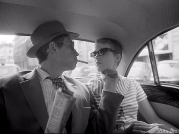 Movie still from “Breathless” (1960), directed by Jean-Luc Godard – A man and a woman sitting in the back of a car; Medium shot, Low angle