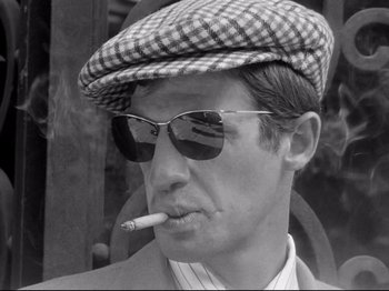 Movie still from “Breathless” (1960), directed by Jean-Luc Godard – A black and white photo of a man smoking a cigarette; Close Up shot, Low angle