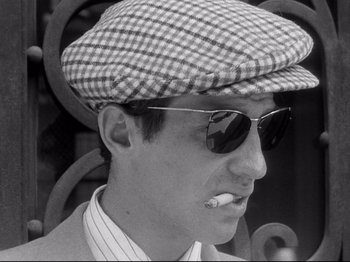 Movie still from “Breathless” (1960), directed by Jean-Luc Godard – A black and white photo of a man smoking a cigarette; Close Up shot, Low angle