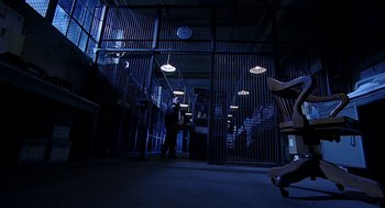 Movie still from “Bride of Chucky” (1998), directed by Ronny Yu – A man standing in a dark room next to stairs; Wide shot, Low angle