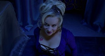 Movie still from “Bride of Chucky” (1998), directed by Ronny Yu – A woman with blonde hair wearing a purple dress; Medium shot, High angle