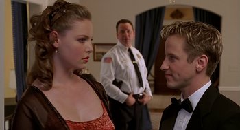 Movie still from “Bride of Chucky” (1998), directed by Ronny Yu – A man and a woman standing next to each other in front of another man; Close Up shot, Over the shoulder angle