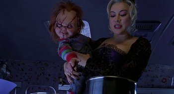 Movie still from “Bride of Chucky” (1998), directed by Ronny Yu – A woman holding a chucky doll over a pot; Medium shot, Overhead angle