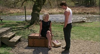 Movie still from “Bride of Chucky” (1998), directed by Ronny Yu – A woman sitting on top of a trunk next to a man; Wide shot, Over the shoulder angle