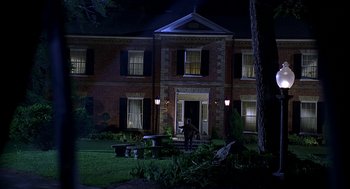 Movie still from “Bride of Chucky” (1998), directed by Ronny Yu – A person standing in front of a building at night; Extreme Wide shot, Low angle