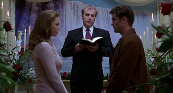 Movie still from “Bride of Chucky” (1998), directed by Ronny Yu – Two men and a woman standing next to each other holding a book; Medium shot, Low angle
