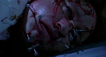 Movie still from “Bride of Chucky” (1998), directed by Ronny Yu – A person's face covered in blood and nails; Extreme Close Up shot, Overhead angle