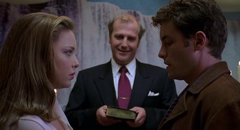 Movie still from “Bride of Chucky” (1998), directed by Ronny Yu – A man in a suit holding a box with two women; Medium shot, Over the shoulder angle