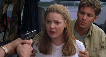 Movie still from “Bride of Chucky” (1998), directed by Ronny Yu – A woman holding a gun in front of a man; Close Up shot, Over the shoulder angle