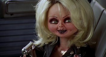 Movie still from “Bride of Chucky” (1998), directed by Ronny Yu – A creepy doll is holding a gun in her hand; Close Up shot, Low angle