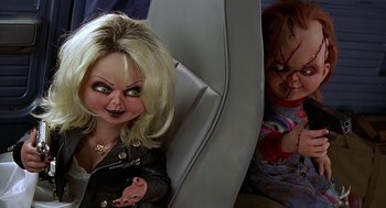 Movie still from “Bride of Chucky” (1998), directed by Ronny Yu – A doll of a woman and a doll of a child in a car seat; Medium shot, High angle