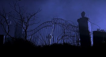 Movie still from “Bride of Chucky” (1998), directed by Ronny Yu – A gate that has a barbed wire fence around it; Wide shot, Low angle