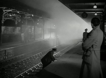 Movie still from “Brief Encounter” (1945), directed by David Lean – A man standing on a train platform next to a train; Wide shot, Low angle