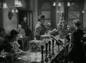 Movie still from “Brief Encounter” (1945), directed by David Lean – A group of people sitting around a bar; Wide shot, High angle