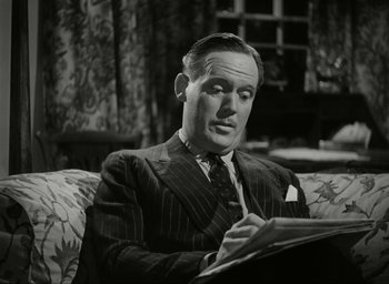 Movie still from “Brief Encounter” (1945), directed by David Lean – A man sitting on top of a couch in a room; Close Up shot, High angle