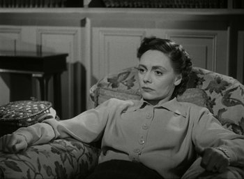Movie still from “Brief Encounter” (1945), directed by David Lean – An older woman sitting on a couch holding a remote control; Medium shot, High angle