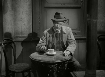 Movie still from “Brief Encounter” (1945), directed by David Lean – A black and white photo of a man sitting at a table with a cup of coffee; Medium shot, High angle
