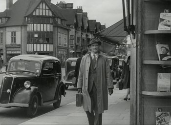 Movie still from “Brief Encounter” (1945), directed by David Lean – An old photo of a man walking down the street; Wide shot, Low angle