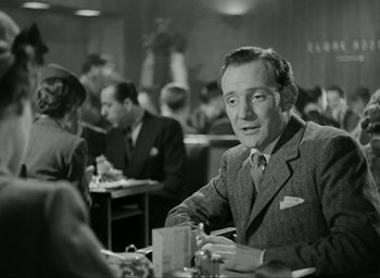 Movie still from “Brief Encounter” (1945), directed by David Lean – A man sitting at a table in front of other people; Medium shot, Over the shoulder angle