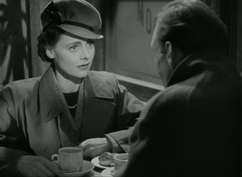 Movie still from “Brief Encounter” (1945), directed by David Lean – An old photo of a woman sitting at a table with a man; Medium shot, Over the shoulder angle