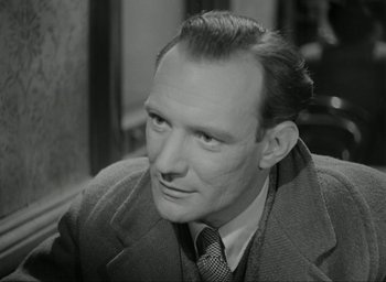 Movie still from “Brief Encounter” (1945), directed by David Lean – An old black and white photo of a man in a suit and tie; Close Up shot, High angle