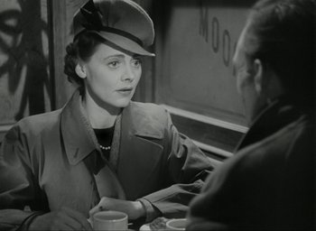 Movie still from “Brief Encounter” (1945), directed by David Lean – An old photo of a woman sitting at a table talking to a man; Medium shot, Over the shoulder angle